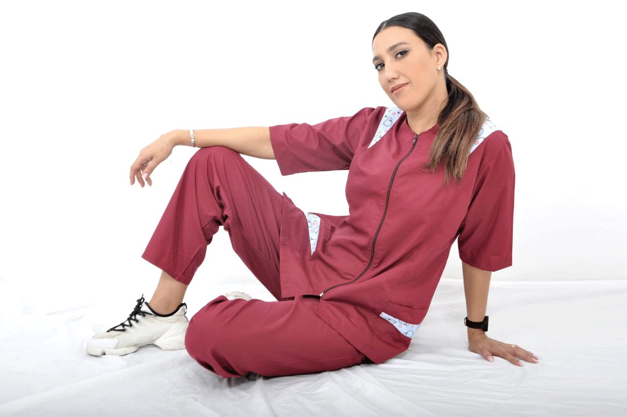 Une infirmière portant une blouse médicale blanche avec une croix rouge brodée, illustrant l'importance des vêtements professionnels dans le domaine de la santé. Les vêtements professionnels santé et médical de Good Uniform offrent confort, durabilité et conformité aux normes d'hygiène, permettant aux professionnels de la santé de travailler en toute confiance. Personnalisez vos tenues avec notre service de broderie pour une identification claire de votre équipe médicale. Optez pour des vêtements qui allient style et fonctionnalité pour une pratique médicale réussie.