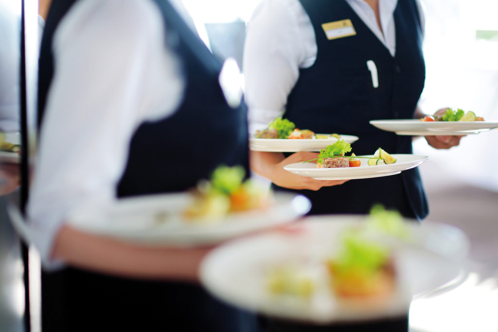 Waiter carrying plates with meat dish on some festive event, party or wedding reception