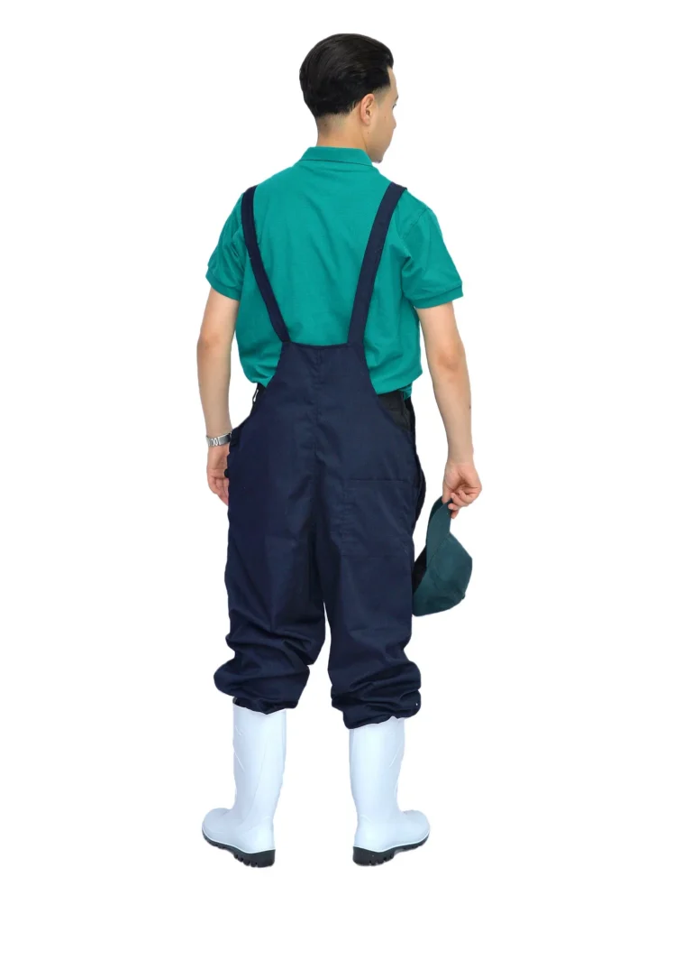 Salopette bleu marine et polo vert vus de dos, bottes blanches