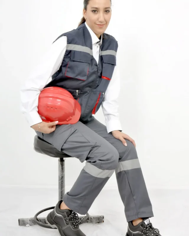 Homme en tenue de travail grise et rouge tenant un casque de chantier rouge