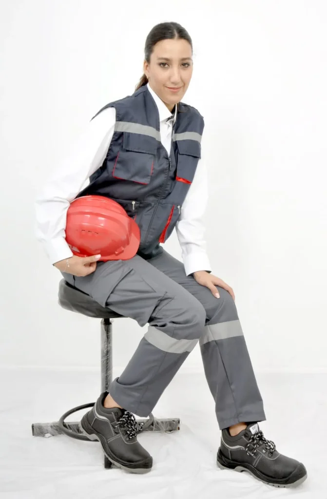 Homme en tenue de travail grise et rouge tenant un casque de chantier rouge
