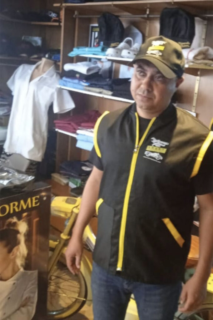 Livreur en gilet noir à liserés jaunes et casquette brodée